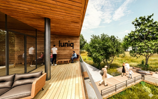 Ein Holzbalkon auf dem mehrere Personen sitzen und davor eine grüße Landschaft mit Holzsteg und laufenden Personen. | © BIS / Tim David Müller-Zitzke