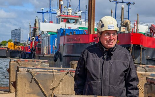 Ein Mann mit einem Helm steht vor einem Schiff | © BIS mbH