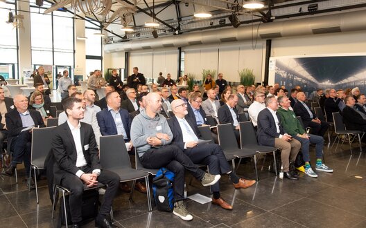 Eine Gruppe von Menschen sitzen auf Stühlen in einer Reihe und schauen nach vorne zu einer Bühne | © BIS / W. Scheer