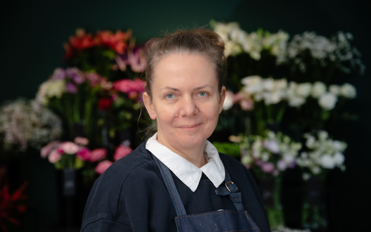Eien Frau lächelt in die Kamera, im Hintergrund sieht man Blumen. | © BIS Bremerhaven/ W. Heumer 