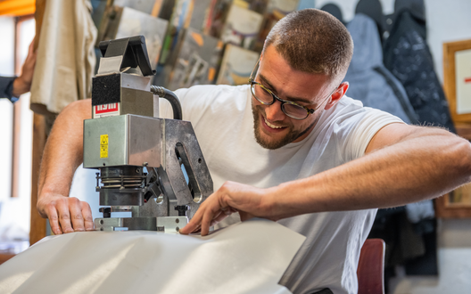 Ein junger Mann bedient eine Industrienähmaschine und lächelt. | © BIS Bremerhaven/ aheads GmbH