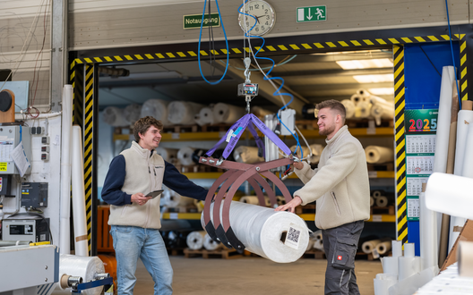 Zwei Männer transportieren eine Rolle mit Filterstoff.