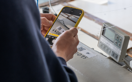 Ein Mann hält ein Handy in der Hand und scannt damit einen Auftrag. | © aheads/BIS Bremerhaven