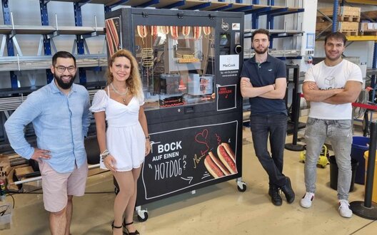 Das vierköpfige Team von MeiCook. In der Mitte steht der Hot-Dog-Automat | © MeiCook